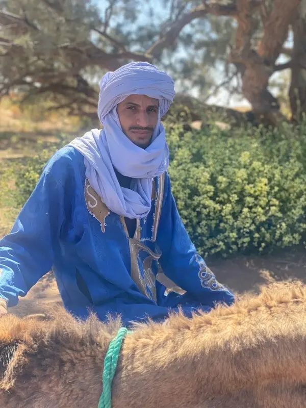 Mohamed, Sahara camel handler sitting beside his camel