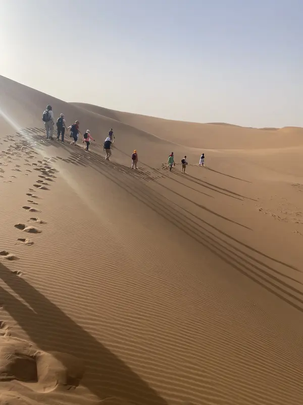 Groupe de trekkeurs longeant une dune du Sahara marocain guides vrais nomades ADN Sahara M'Hamid