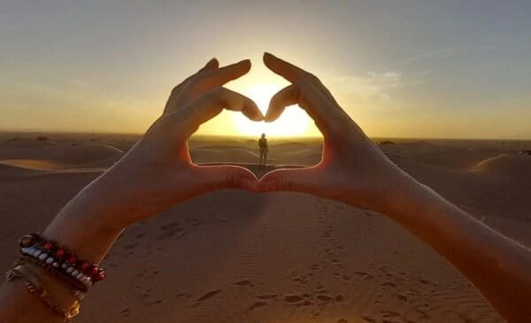 Two hands making a heart in sunset.