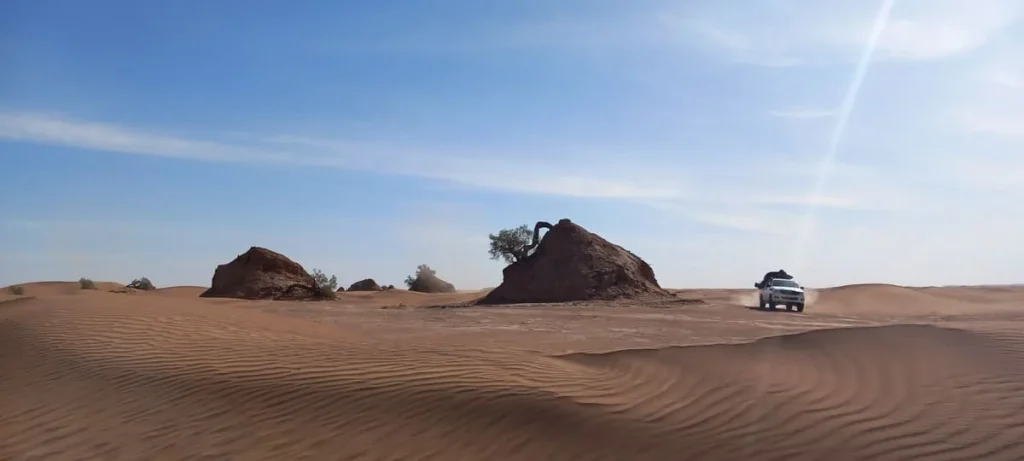 A 4x4 crosses rolling sand waves in the Erg Chegaga desert, capturing the quiet beauty of the Moroccan Sahara