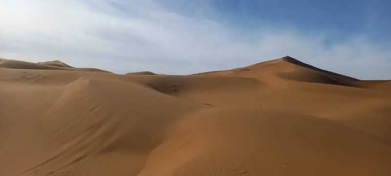 Dunes immaculées de l’Erg Chegaga sous un ciel nuageux, évoquant le désert sauvage marocain.