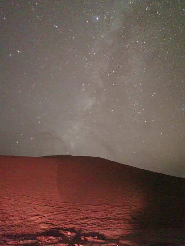 Milky Way and starry night sky over a traditional nomad bivouac in the Moroccan Sahara.