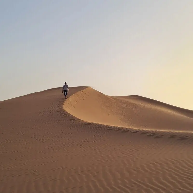 Solo trekker climbing a dune at sunset — Erg Chigaga Sahara Morocco, 4x4 desert tour ADN Sahara M'Hamid