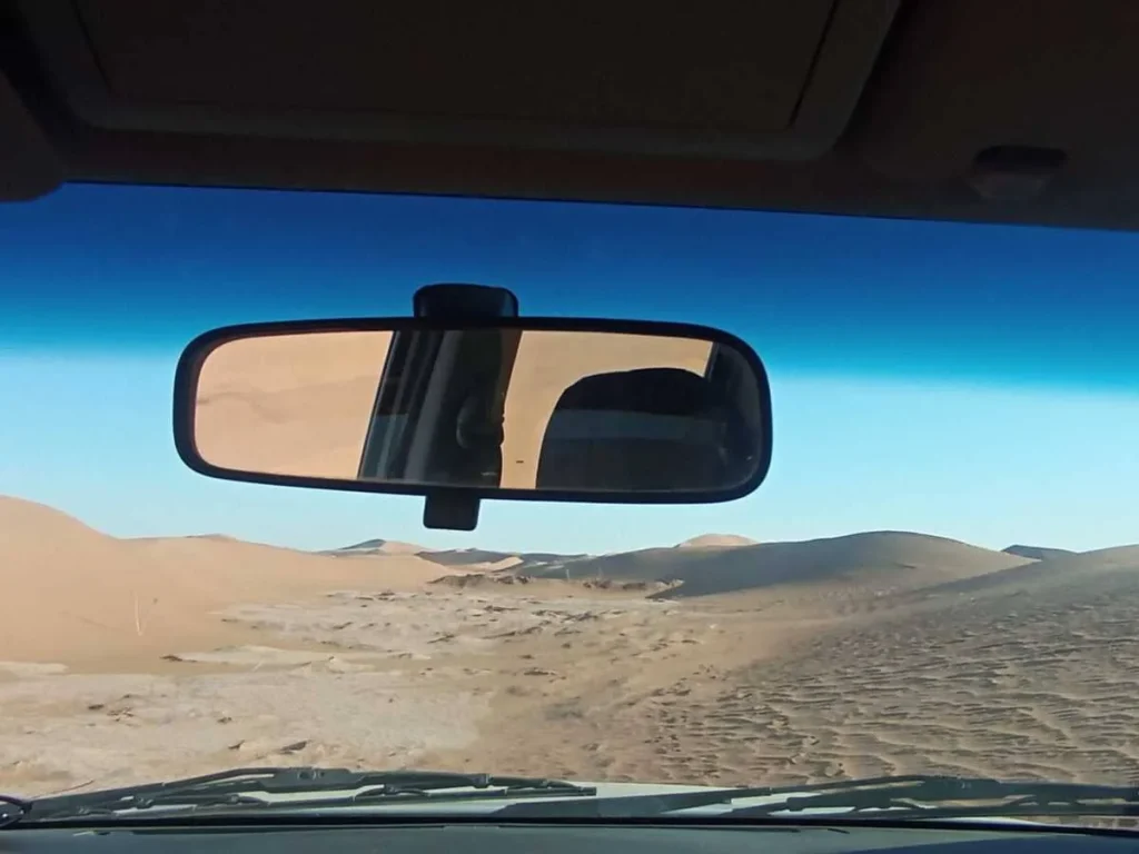 During a 3-day desert tour, the view from the 4x4 opens onto sandy tracks and quiet dunes, leading toward Erg Chegaga under a vast blue sky