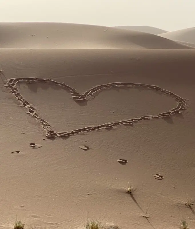 Souvenir d’une excursion 4x4 dans le Sahara depuis M’Hamid El Ghizlane avec un cœur dessiné dans le sable et une ambiance authentique du désert marocain