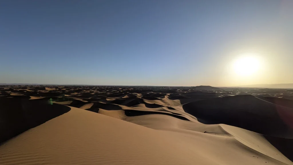 Vue depuis l'Erg Chegaga au soleil déclinant, avec un jeu d'ombres sur la mer de dunes du Sahara marocain.