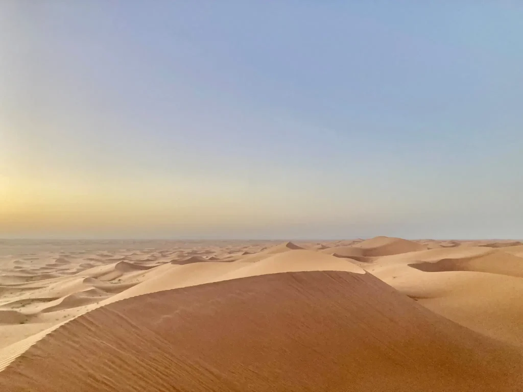 Pastel sunrise over the pale ochre sand dunes of Erg Chegaga, Morocco, viewed from the highest dune.
