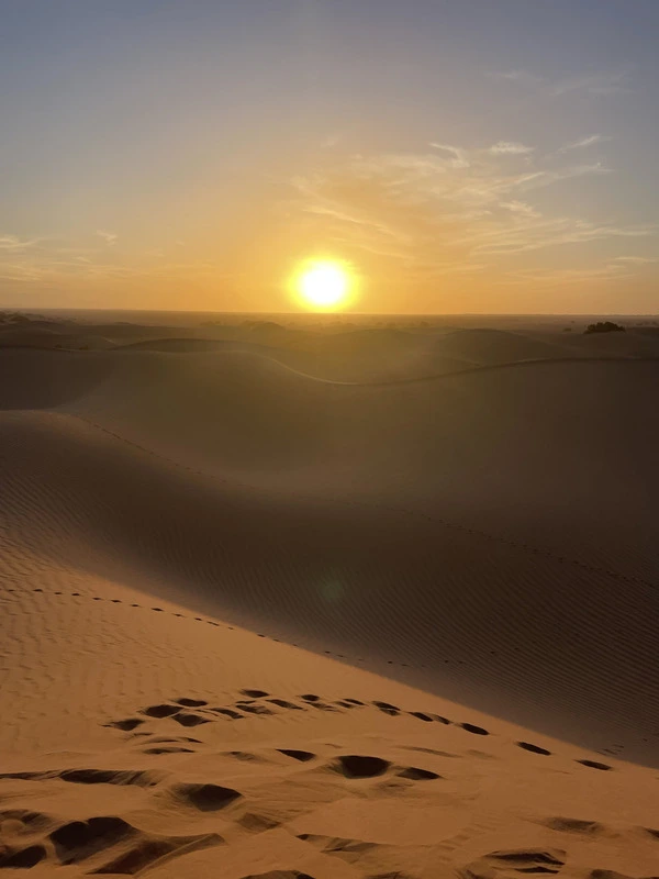 Footsteps leading up an Erg Zahar dune at sunset during a 6-day desert trek in Morocco
