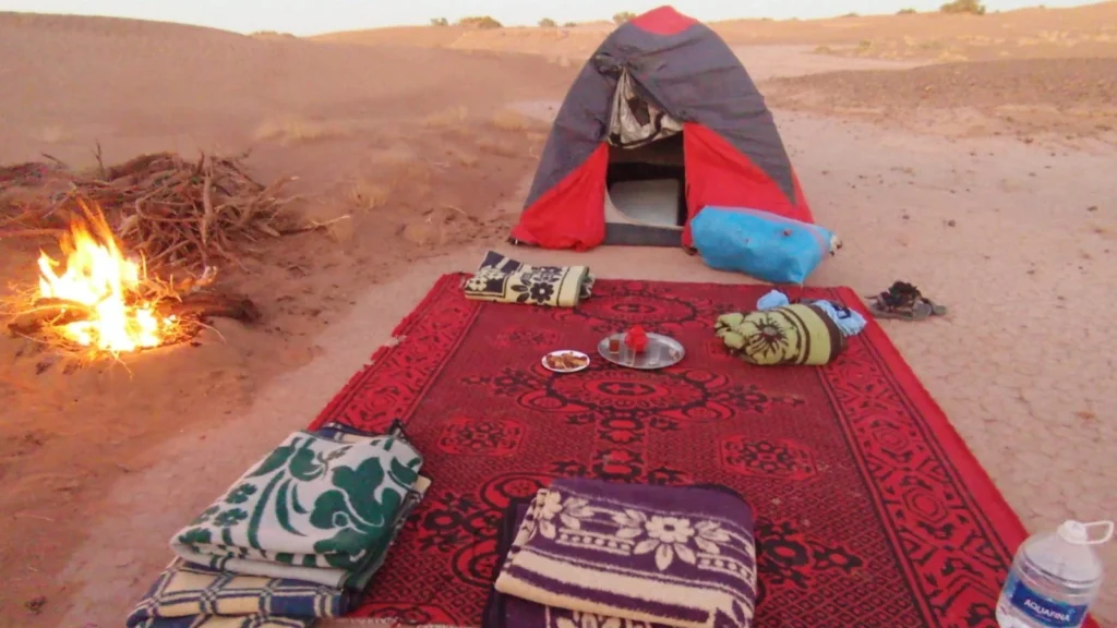 Traditional Moroccan camp with tea, carpet and trek tent at dusk during a 6-day Erg Chegaga trek in Morocco 2026