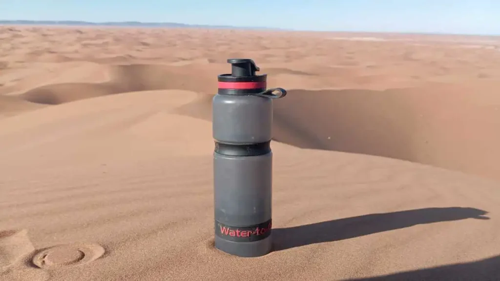 Water bottle on a golden dune overlooking the Erg Chegaga desert during a 6-day trek in Morocco